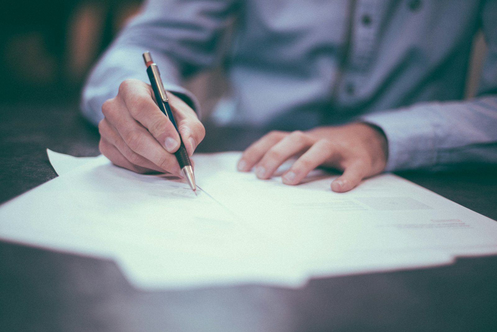 Close-up of a person filling out insurance paperwork and an appeal form with a pen